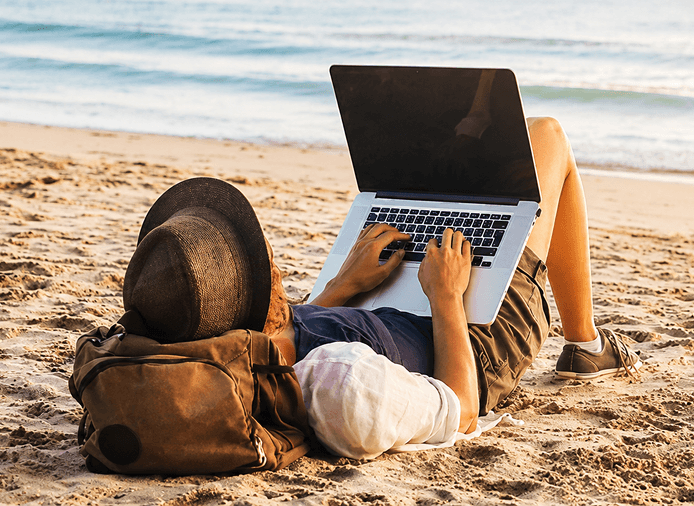 Remote worker relaxing on the beach in Crete with a laptop
